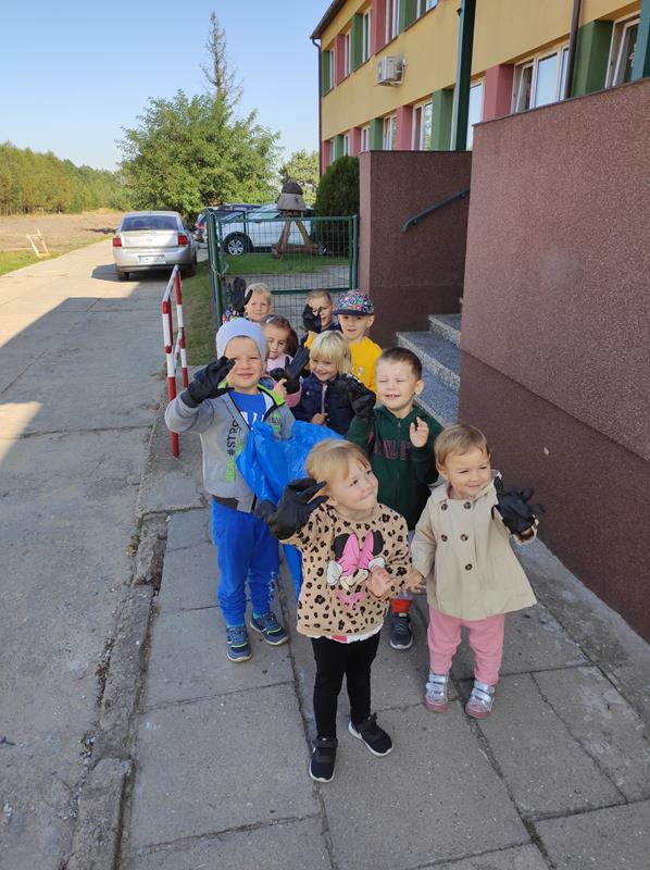 Grupa Krasnoludków sprząta teren przy budynku szkoły